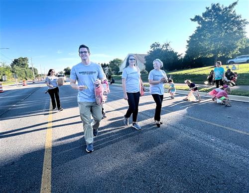 4 members of the instruction team walking with bags of candy in parade